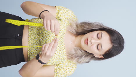 Vertical-video-of-Unhappy-person-measuring-her-weight-with-a-tape-measure.